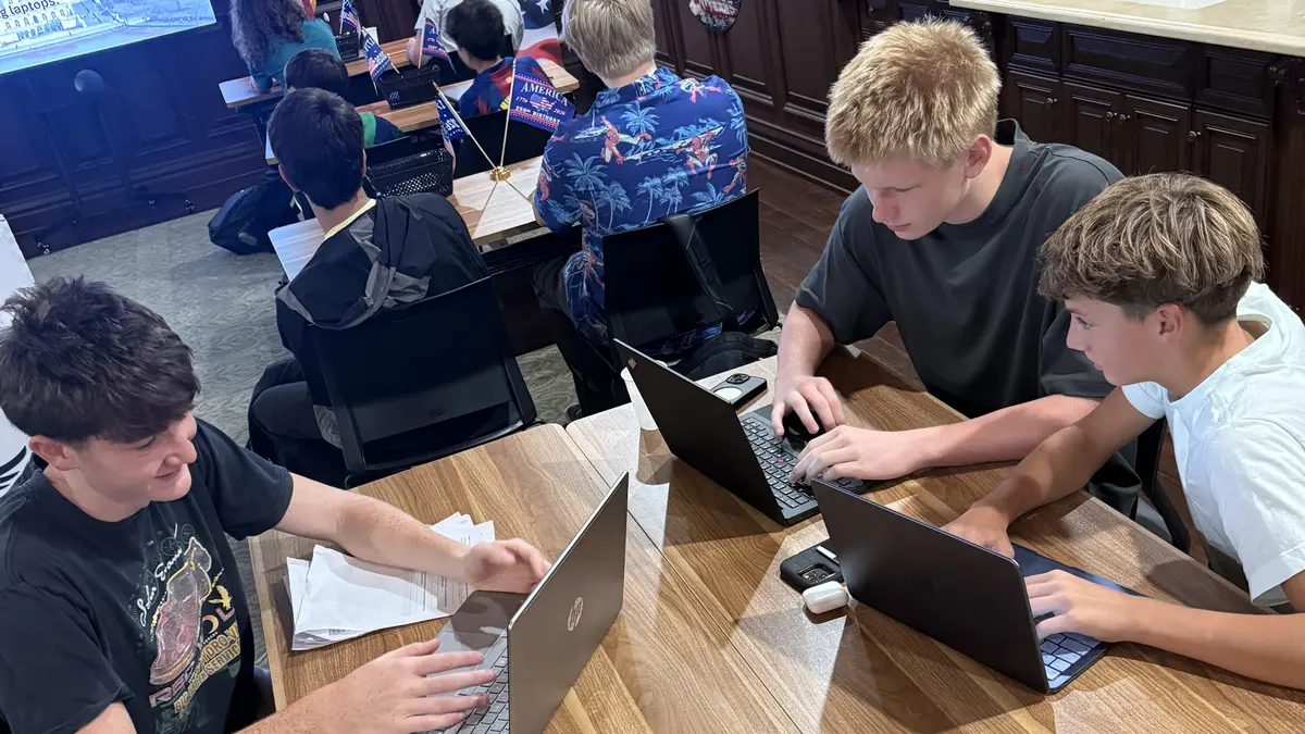 Freedom Ave Maria students working on laptops around the classroom table