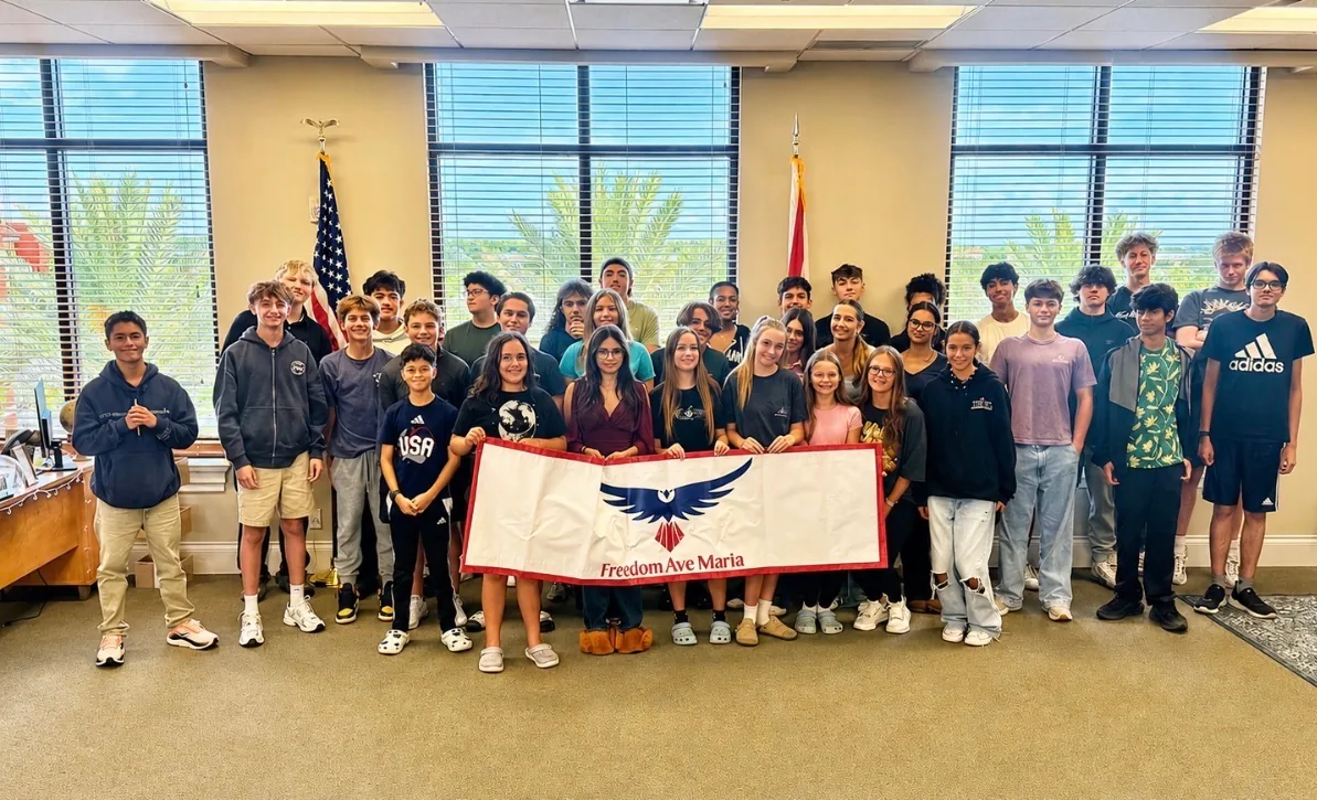 Freedom Ave Maria students holding the campus banner