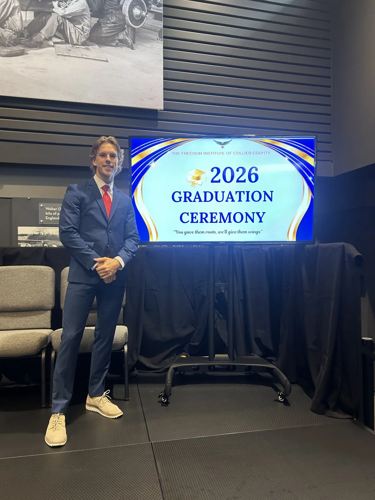 Christophe Farrell, Class of 2024, beside the 2026 Graduation Ceremony screen