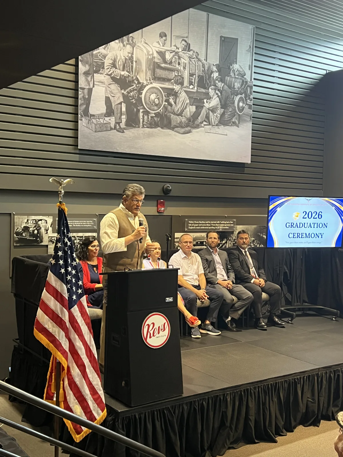 A speaker at the podium during the 2026 graduation ceremony at Revs Institute
